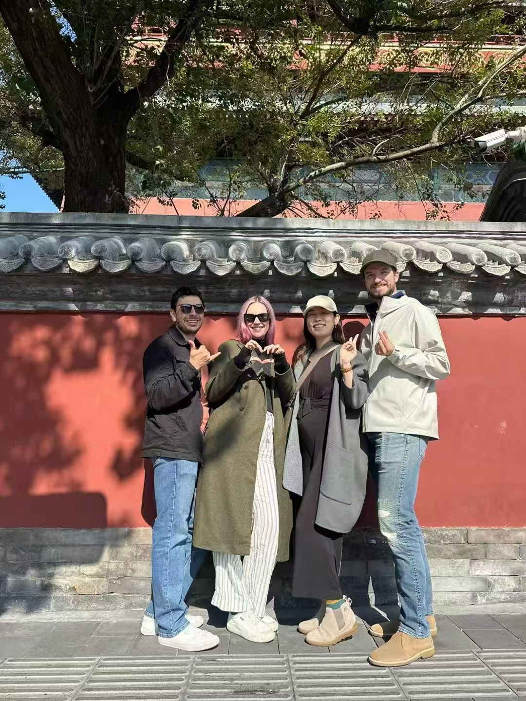 Travelers walking beside a red wall in Beijing