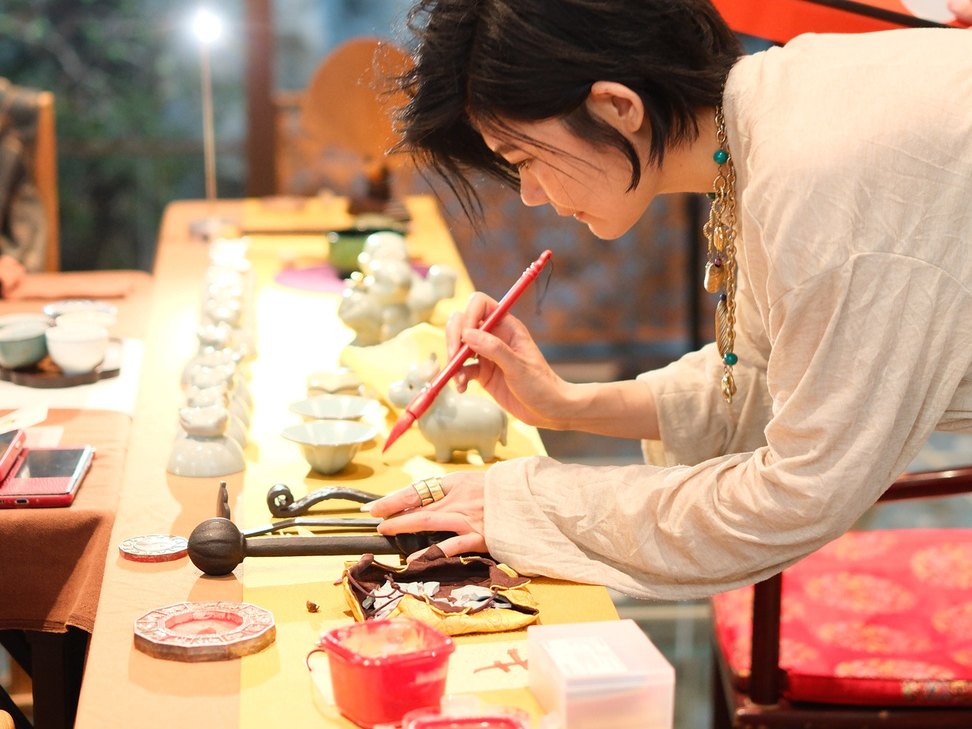 Guest writing a Chinese zodiac character on a porcelain piece