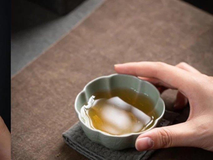 Hand holding a celadon-toned Ru-style porcelain cup