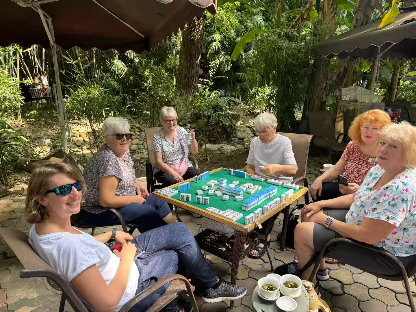 International guests joining a local mahjong moment in a Chengdu teahouse garden