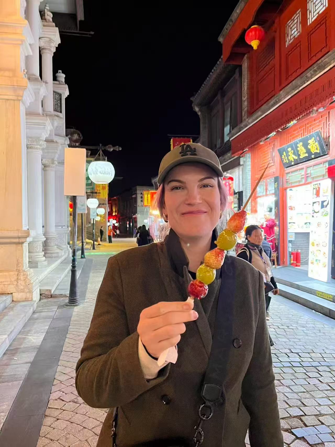 A traveler trying tanghulu on a Chinese street at night